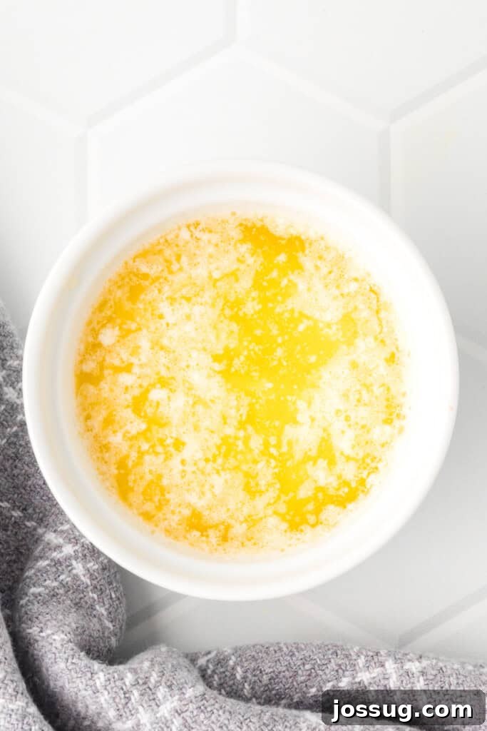 Rich melted butter in a pristine white bowl, perfectly prepared to be combined with lemon and salt for a simple, elegant dipping sauce.