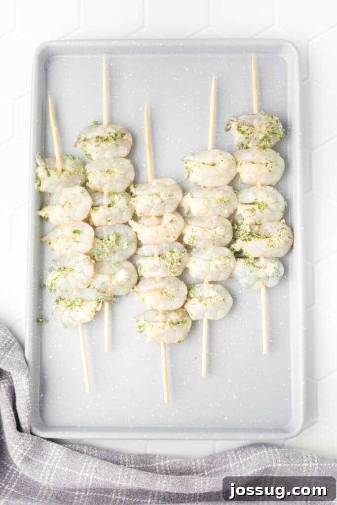 Raw shrimp skewered and elegantly arranged on a gray tray, seasoned and gleaming, perfectly poised for grilling.