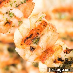 Square crop of grilled shrimp skewers with visible grill marks and fresh herbs, ready to serve.