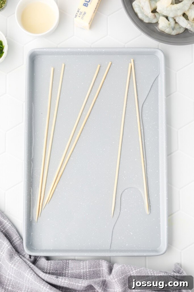 Wooden skewers soaking in water on a gray tray, a crucial step to prevent burning during grilling.