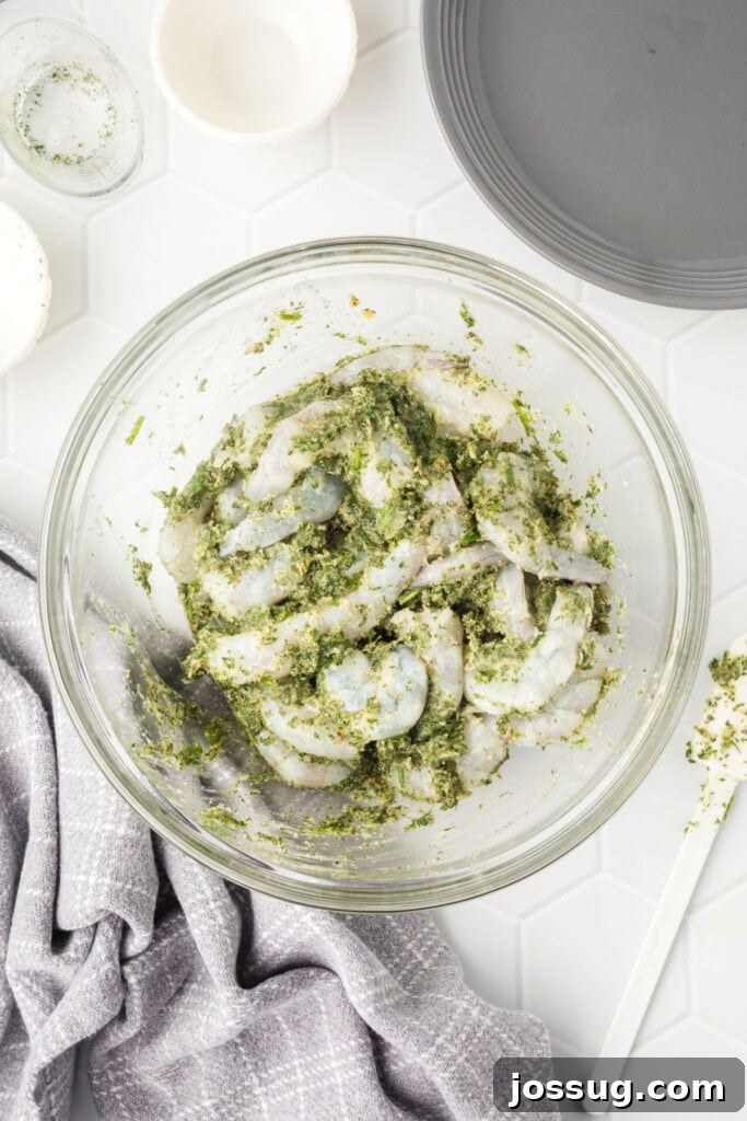 Raw shrimp being gently stirred into the grilled shrimp marinade in a glass bowl, ensuring each piece is thoroughly coated.