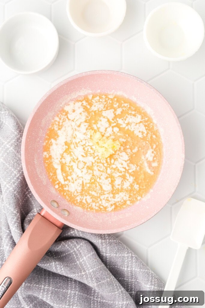 Butter melting gently in a charming pink pan on the stovetop, preparing for the rich lemon garlic dipping sauce.