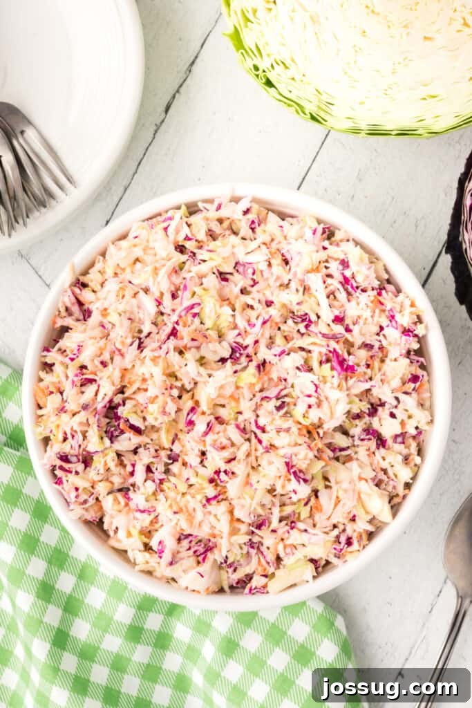 White bowl filled with freshly made creamy coleslaw placed on a green gingham napkin.