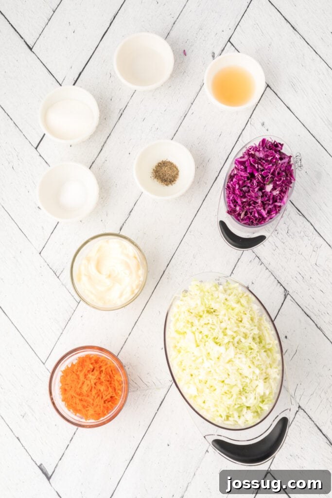 Overhead view of small bowls with coleslaw ingredients, including green and red cabbage, carrots, mayo, and seasonings on a white wooden surface.