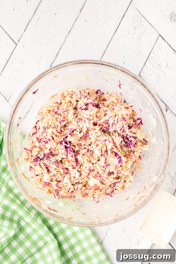 Fully mixed coleslaw in a glass bowl, showing creamy texture and colorful vegetables.