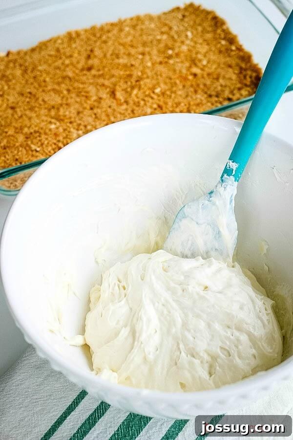 Creamy cheesecake filling in a bowl, ready for Orange Gelatin Pretzel Salad