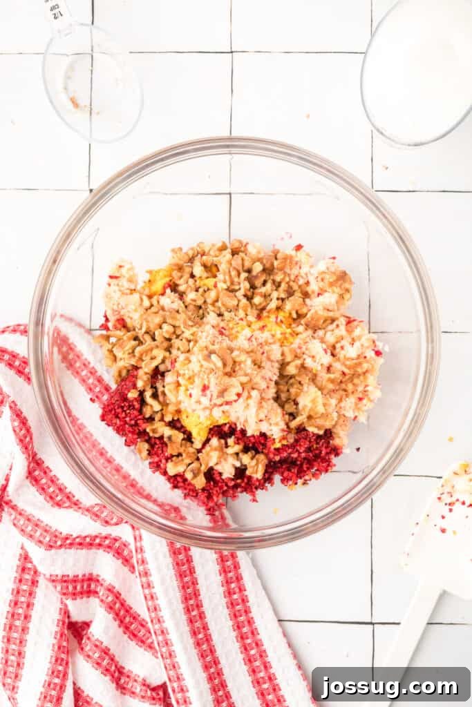 Cranberry Burst 13 Mixing bowl with chopped cranberries, oranges, apples, and chopped walnuts layered on top, ready to be stirred together.