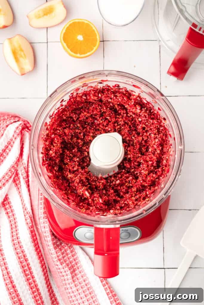 Cranberry Burst 5 Finely chopped orange pieces inside the red food processor, showing a bright yellow-orange mixture.