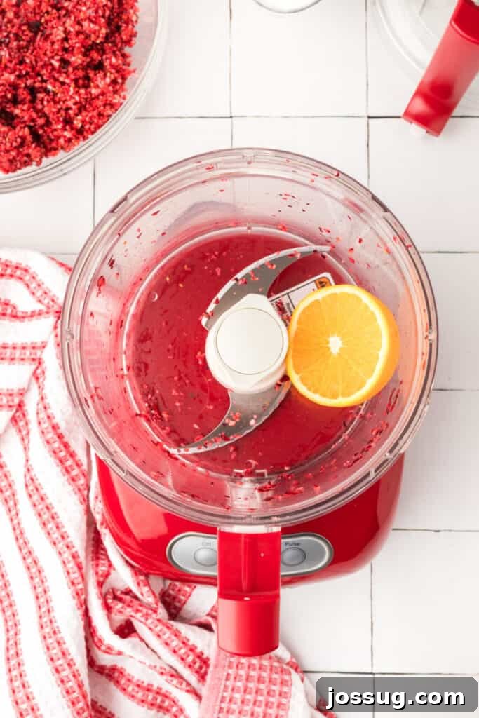 Cranberry Burst 7 Finely chopped orange pieces inside the red food processor, showing a bright yellow-orange mixture.