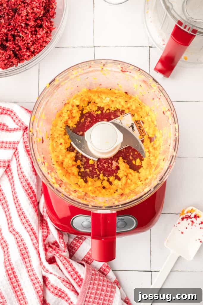Cranberry Burst 8 Finely chopped orange pieces inside the red food processor, showing a bright yellow-orange mixture.