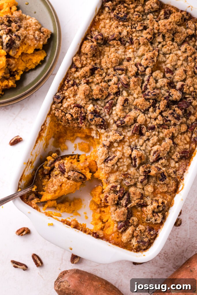 A golden brown sweet potato casserole with a generous pecan topping, ready to be served from a baking dish.