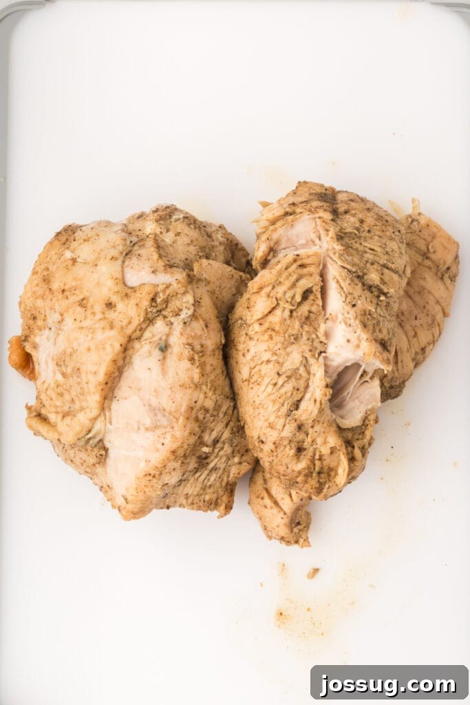 Cooked turkey breast resting on a white cutting board after being removed from the Instant Pot.