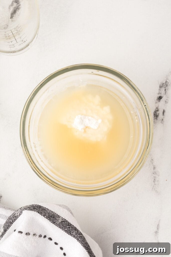 Glass bowl with cornstarch and broth mixture before whisking together to form slurry.