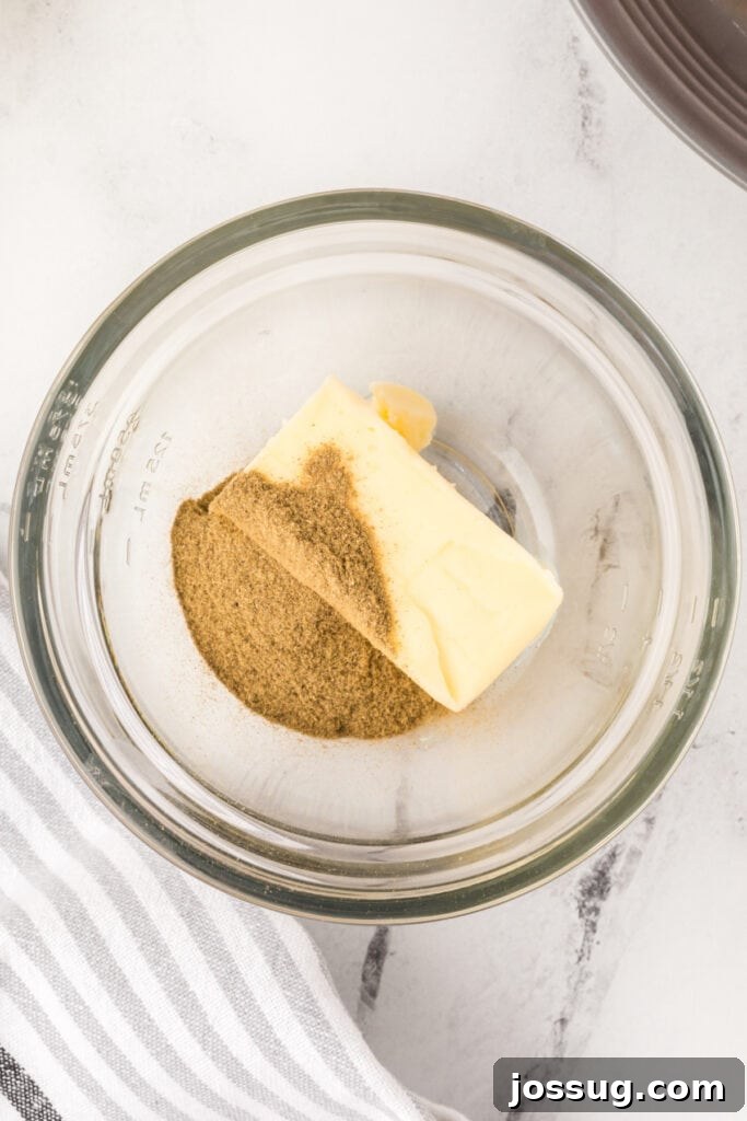 Butter and poultry seasoning in a glass bowl ready to be mixed for turkey seasoning butter.