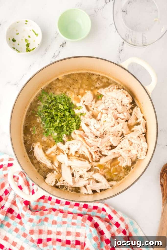Hearty White Chicken Chili 11 Shredded chicken and fresh cilantro added to the pot of chili before stirring.