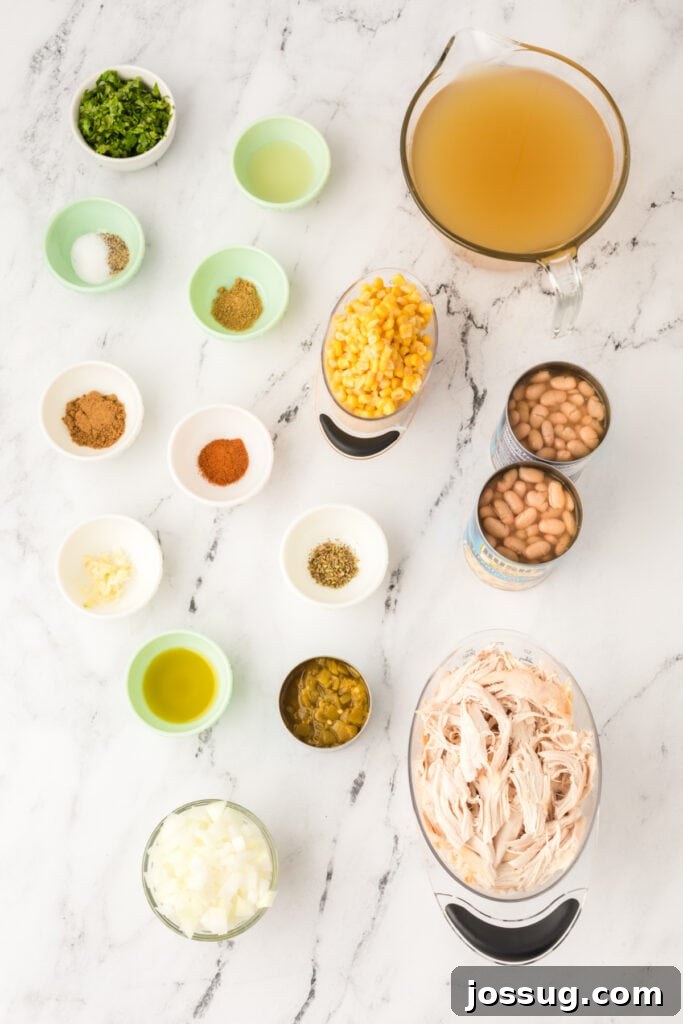 Hearty White Chicken Chili 3 Overhead shot of White Chicken Chili ingredients in small bowls and measuring cups on a marble surface, including corn, beans, broth, and spices.
