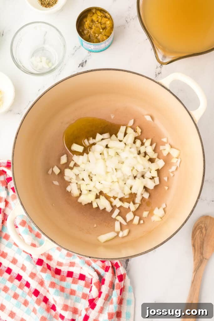 Hearty White Chicken Chili 4 Chopped onions added to olive oil in a large cream-colored dutch oven, ready to sauté.