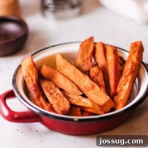 A plate of golden, crispy oven-baked sweet potato fries seasoned with paprika and garlic powder.