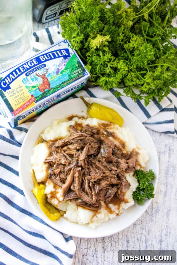 Plated Mississippi Pot Roast with mashed potatoes, garnished with fresh herbs and a pat of Challenge Butter