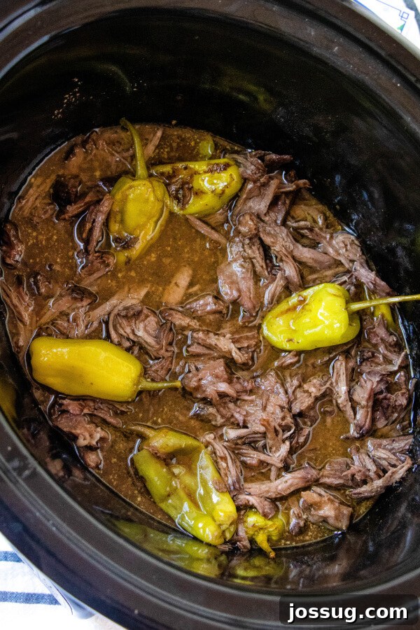 Shredded Mississippi Pot Roast in a slow cooker with peppers