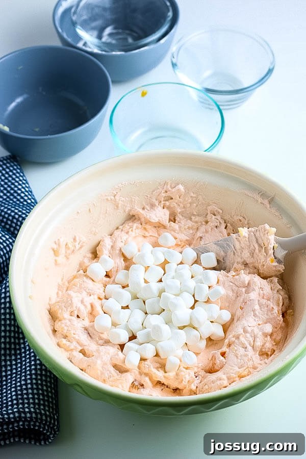 Creamsicle Dream Dessert 7 marshmallows added to the mixed orange fluff salad ingredients in a bowl