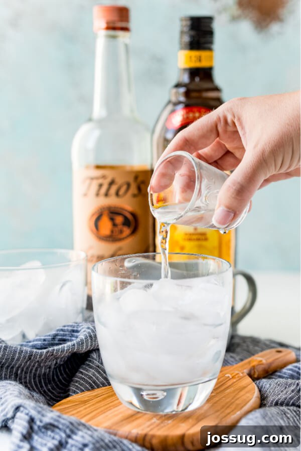Velvet Russian 3 Pouring vodka into a glass over ice for a White Russian