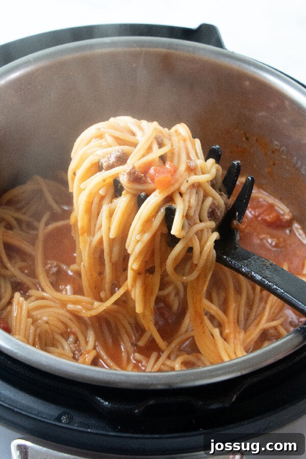 A ladle scooping out perfectly cooked Instant Pot Spaghetti, showcasing the rich sauce and tender noodles.
