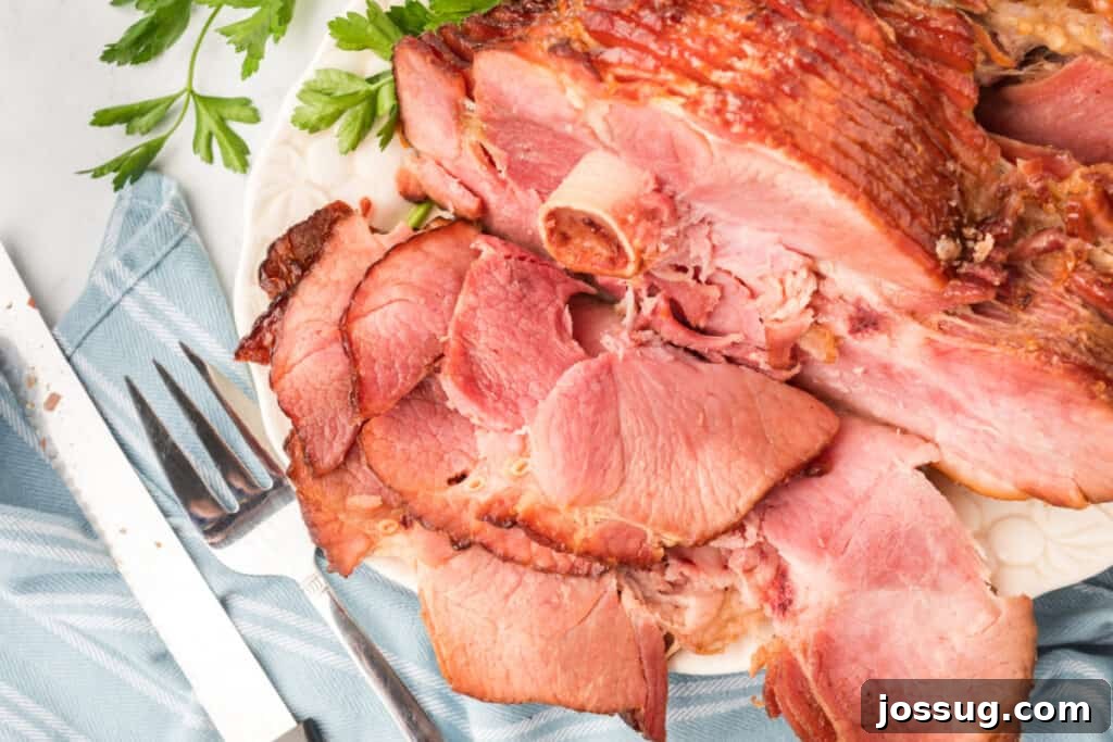 Honey baked glazed ham on a large serving platter, ready to be carved