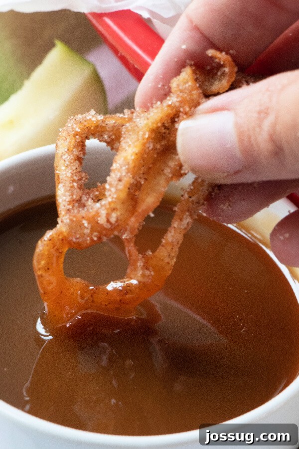 Sweet Apple Cinnamon Fry Curls 8 a curly apple fry being dipped into caramel sauce