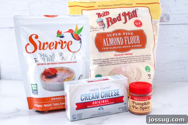 Pumpkin Pie Keto Bites 3 Ingredients laid out on a table for making keto pumpkin pie fat bombs, including cream cheese, Swerve sweetener, almond flour, and pumpkin pie spice.
