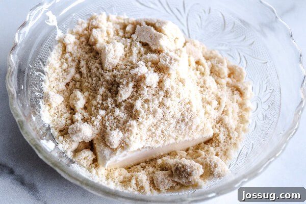 Pumpkin Pie Keto Bites 4 Cream cheese, Swerve granular sugar, and almond flour being mixed in a bowl.