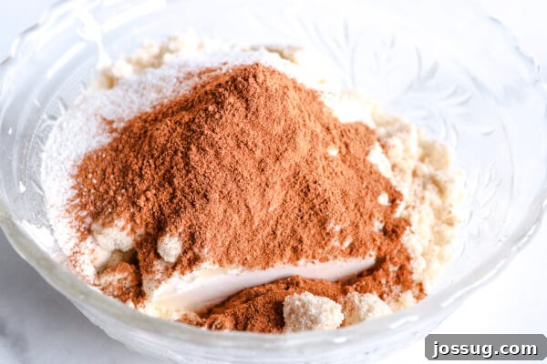 Pumpkin Pie Keto Bites 5 Pumpkin pie spice and other spices being added to the cream cheese mixture in a bowl.