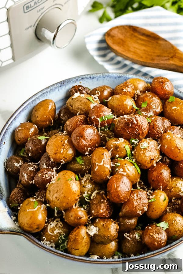 Slow Cooked Garlic Parmesan Potatoes 2 slow cooker garlic parmesan potatoes in serving bowl with crockpot and wooden spoon in background
