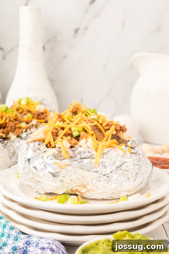 Idaho Spud Tacos 2 Two Idaho Tacos on stacked plates, featuring a golden baked potato filled with seasoned ground beef, melted cheese, and fresh green onions.