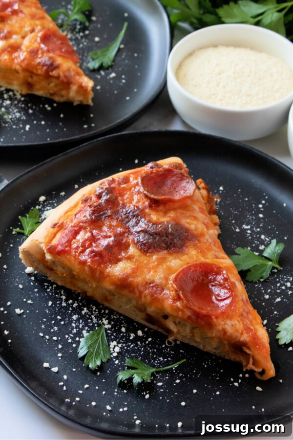 A perfectly baked pizza slice resting on a black plate, showcasing its golden-brown crust, melted cheese, and fresh toppings.