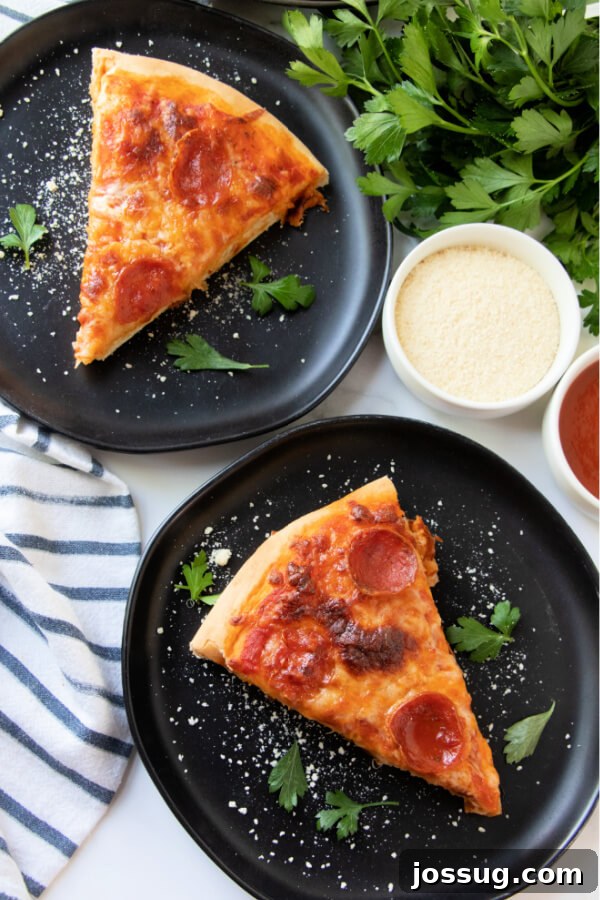 Two plates, each holding a mouth-watering slice of homemade pizza, garnished with fresh basil, ready to be enjoyed.