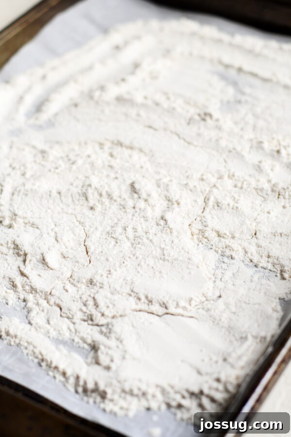 All-purpose flour spread evenly on a baking sheet, ready for toasting