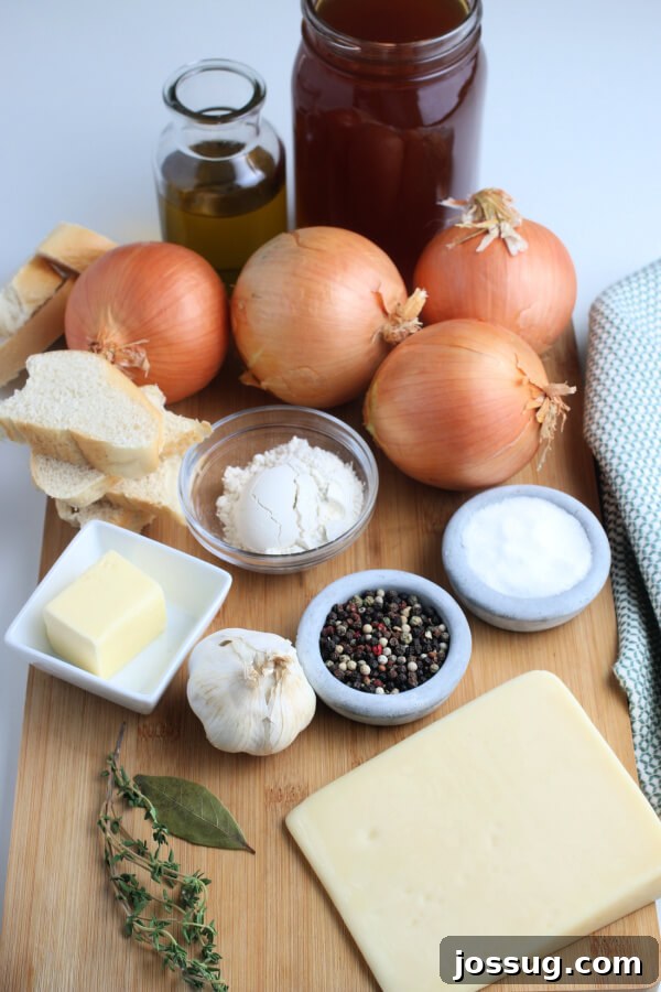Golden Gratin French Onion Soup 3 A collection of fresh ingredients laid out, ready to make French Onion Soup, including yellow onions, a bundle of thyme, garlic cloves, and French bread.