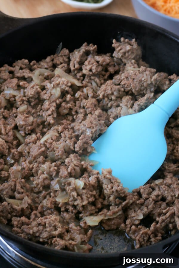 One-Pot Cheesy Beef Mac 4 Ground beef browning in a cast iron skillet with chopped onions.
