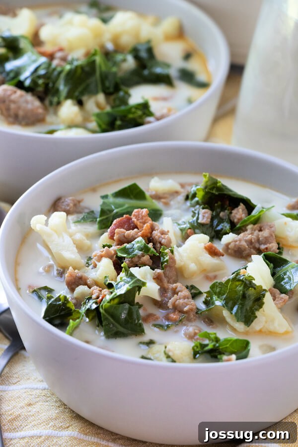A beautifully presented bowl of steaming Low Carb Zuppa Toscana soup, rich with sausage, kale, and cauliflower, ready to be enjoyed.