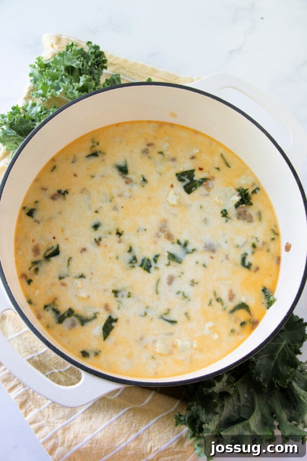 A large pot of creamy low carb Zuppa Toscana soup, brimming with ingredients and simmering gently on the stovetop.