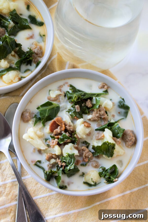 A close-up view of a bowl of creamy Zuppa Toscana, showcasing the tender cauliflower and vibrant kale leaves.