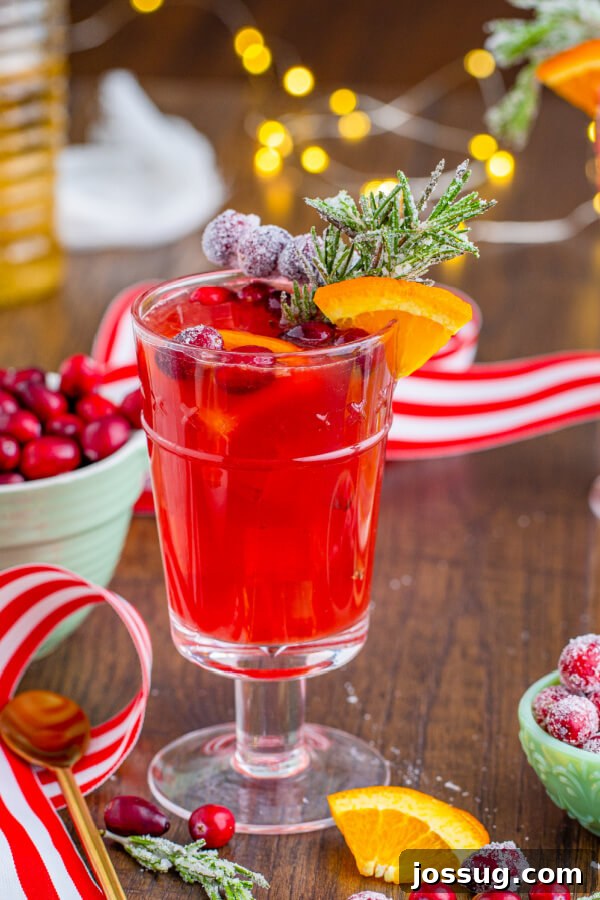 non-alcoholic Christmas drink with festive background, garnished with cranberries and rosemary