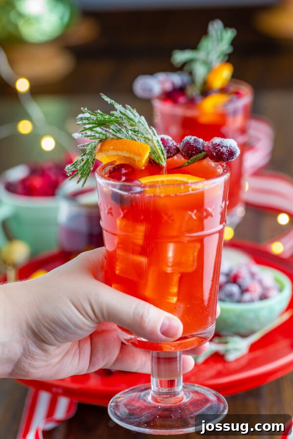 Hand holding a glass of Christmas mocktail with a cozy winter background