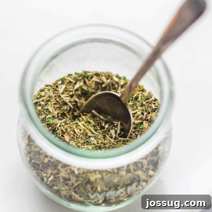 Homemade Italian Seasoning mix in a small jar, with dried herbs.