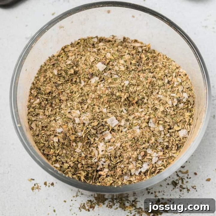 Easy Greek Seasoning Recipe in a small jar, with dried herbs visible.