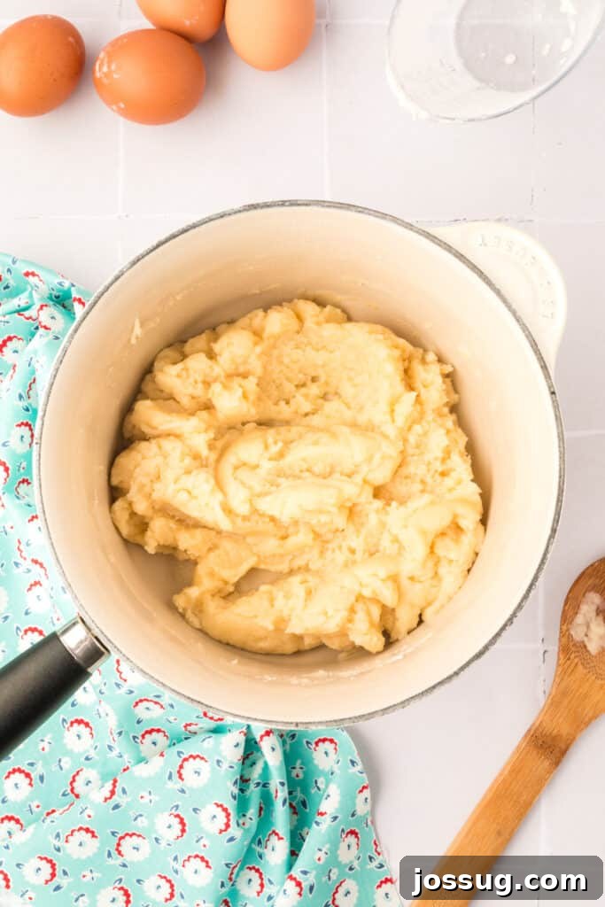 Pillowy Cream Dreams 8 Quickly stir in flour with a wooden spoon into the boiling mixture, continuing to cook and stir constantly until a film forms on the bottom of the pan, indicating the dough is ready.