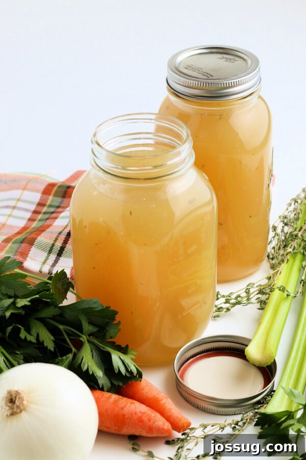 Rich Homemade Turkey Stock 6 Two jars of homemade turkey stock, one with a paper label, surrounded by fresh herbs and vegetables, showcasing its freshness and ease of storage.