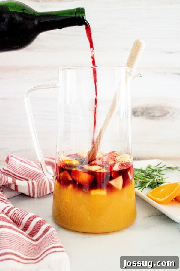 orange juice and red wine being poured over the fruit in the pitcher