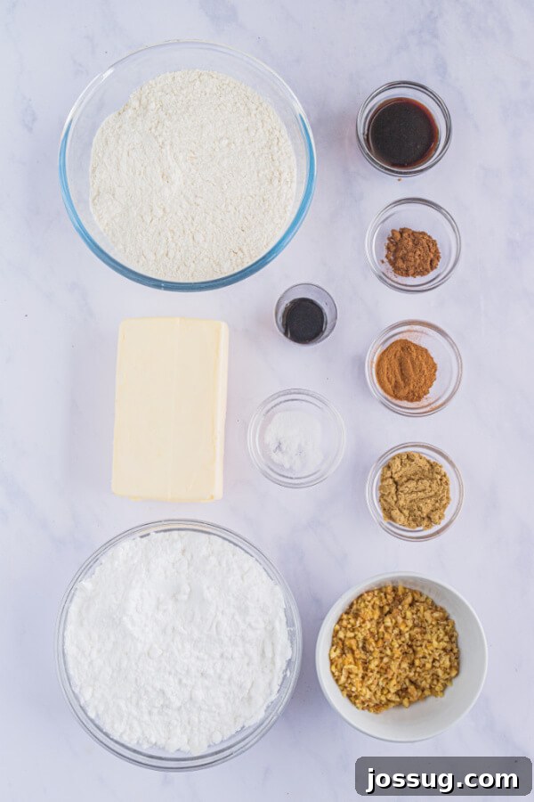 An organized display of fresh ingredients for baking Gingerbread Pecan Snowballs, including butter, powdered sugar, flour, various spices, and pecans.